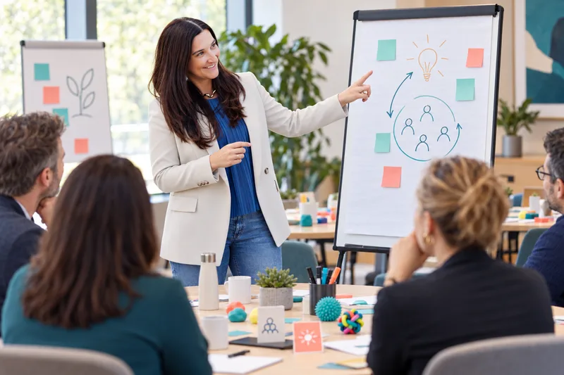 Illustration of Hélène facilitating a workshop with participants at round tables.